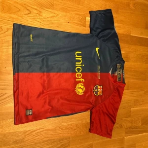 FC Barcelona Messi Roma 2009 - Säljer en officiell FC Barcelona matchtröja från Nike med Messi 10 på ryggen. Tröjan har klassisk röd och mörkblå färg, gula detaljer och klubbmärke på bröstet. Tillverkad i lätt och ventilerande polyester med korta ärmar och tryckta loggor.