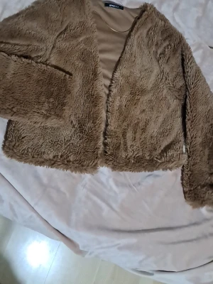 Beige pälsjacka från Gina Tricot - Säljer en fluffig och mjuk beige pälsjacka från Gina Tricot i storlek S. Jackan har långärmade ärmar och är croppad i modellen. Perfekt för dig som gillar en cozy och trendig look med lite extra attityd.