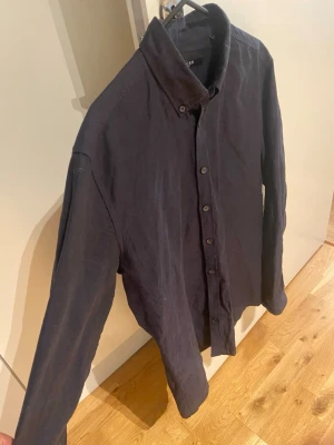 Mörkblå skjorta från Tiger of Sweden - Snygg mörkblå skjorta från Tiger of Sweden i mjukt linne. Klassisk krage, knappar hela vägen och långärmad modell. Perfekt för dig som gillar stilrena och enkla plagg med skön passform.