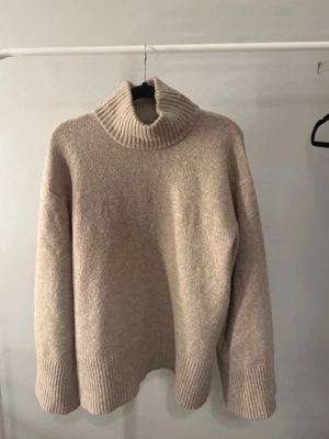 Beige stickad tröja med krage från Bubbleroom - Säljer en oversized beige polotröja från Bubbleroom i mjukt stickat material. ☺️