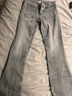 Grå bootcut jeans med stora fickor - Hejsan!!💘Säljer ett par grå jeans med bootcut-modell och stora fyrkantiga fickor framtill. Jeansen har markerade sömmar längs benen och klassiska bakfickor. Materialet är jeans och färgen är en tvättad grå ton som ger en avslappnad vibe. Jeansen är använda få gånger och har små små uppsprättningar på jeansen ändor💘