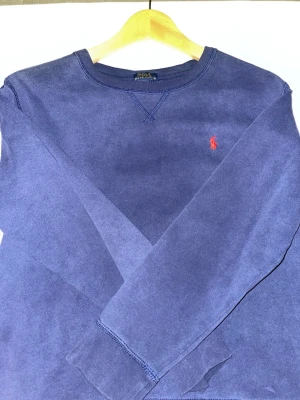 Marinblå tröja från Polo Ralph Lauren - Säljer en marinblå långärmad tröja från Polo Ralph Lauren i storlek L. Tröjan har det klassiska röda broderade logotypen på bröstet och är gjord i mjuk bomull. Perfekt basic med ribbade muddar och rund hals. KOLLA IN MIN PROFIL FÖR MER TRÖJOR! 👕 