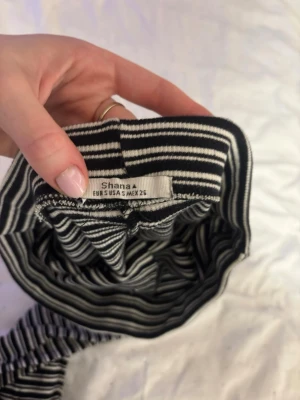 Randig långkjol från Shana - Säljer en svartvit långkjol från Shana i storlek S. Kjolen har smala horisontella ränder och är rak i modellen, vilket ger en clean och stilren look. Perfekt att matcha med en enkel topp eller hoodie för en chill vibe.