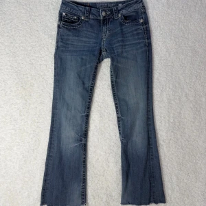 Miss Me jeans – bootcut, stl 27  - Säljer ett par blå bootcut jeans från Miss Me i storlek 27. Jeansen har snygga slitningar, kontrastsömmar och broderade detaljer på fickorna. Klassisk femficksmodell med låg midja och råa benslut. Tillverkade i mjukt denimtyg.