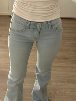 Ljusblå bootcut jeans - Säljer ett par ljusblå jeans med bootcut passform. Klassisk femficksmodell och normal midja. Jeansen är i mjukt denimtyg och har en snygg, enkel look som passar till det mesta. Perfekta för dig som gillar en retrovibe och vill ha ett par jeans som sticker ut lite.