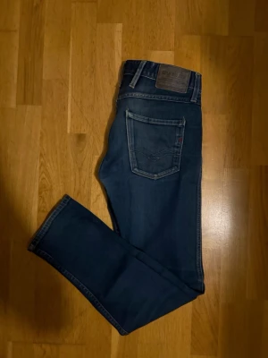 Replay Anbass blå jeans - Säljer ett par snygga Replay Anbass jeans i klassisk blå tvätt. Modellen har raka ben, fem fickor och Replay-logga på bakfickan slim fit.