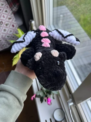 Virkad svart och rosa drake  - Virkad gosedjursdrake i svart med ljusrosa och vita detaljer🖤🩷🤍 OBS:  !Dessa innehåller säkerhetsögon som inte rekommenderas för barn under 3 år!