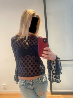 Marinblå meshblus med prickar - Säljer en marinblå meshblus med stora svarta prickar och vida, transparenta ärmar. Blusen är lätt croppad och har en riktigt snygg, luftig känsla. Från etc.etc i storlek M. Superbra skick