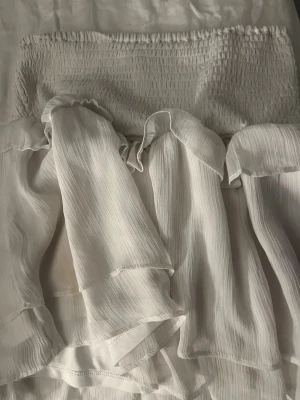 Vit volangkjol💕 - Supersöt vit kjol med bred smockresår i midjan och flera lager tunna volanger. Kjolen har en luftig och flowy känsla, perfekt för varma dagar. Materialet känns lätt och svalt mot huden. 🙌