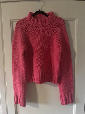 Rosa stickad tröja med hög krage  - Mysig rosa stickad tröja med hög ribbad krage och långa ärmar från KOOKAÏ den är i storlek 2/xxxs men skulle säga att den passar XS-S. Tröjan har en relaxed passform och breda ribbade muddar vid ärmslut och nederkant. Perfekt för kyliga dagar och enkel att styla med jeans eller kjol. 
