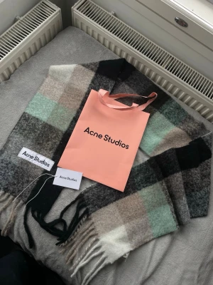 Rutig ullväst Acne Studios - Säljer en rutig väst från Acne Studios i mjuk ullmix. Västen har breda blockrutor i svart, grått, beige, vitt och mintgrönt. Klassisk Acne Studios-label framtill och fransar i nederkant för extra vibe. Perfekt lager-på-lager-plagg för kyliga dagar.