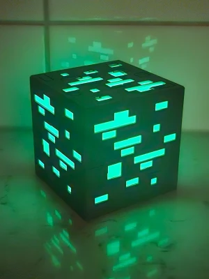 Minecraft-inspirerad LED-kub - Säljer en grå kubformad LED-lampa med pixeligt mönster och grönt sken, inspirerad av Minecrafts emeraldblock. Lampan är gjord i plast och har ett avtagbart lock med plats för ett LED-ljus inuti. Perfekt som nördig inredningsdetalj! Storlek 8x8x8 cm