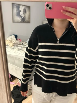 Svartvit randig stickad tröja half zip - Säljer en svart stickad tröja med vita horisontella ränder och half zip-dragkedja i halsen. Tröjan har lång ärm, ribbade muddar och en avslappnad passform. Perfekt för dig som gillar klassisk men chill stil.