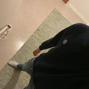 Mörkblå sweatshirt från Moncler - Säljer en stilren mörkblå sweatshirt från Moncler med klassisk rund hals och broderad logga på bröstet. Tröjan har långa ärmar, ribbade muddar och är tillverkad i mjuk bomull. Perfekt för dig som gillar clean och exklusiv streetstyle.