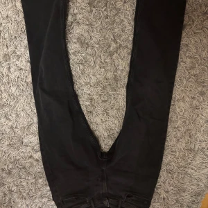 Svarta regular fit jeans 32/32 - Svarta jeans från Adenim i regular fit med klassisk femficksdesign och raka ben. Jeansen är tillverkade i denim och har en enkel, stilren look som passar till det mesta. Storlek 32/32, tillverkade i Indien.