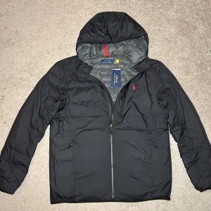 Ralph Lauren Jacka -  Ralph Lauren jacka med tags. Färg svart, Storlek M. Jackan är vattentät, den är gjord av polyester vilket kan vara väldigt skönt och den går att packa ihop till en liten påse som kan vara väldigt praktiskt. Nypris 4295kr, släpper för 1199kr. Snabb affär bättre pris. Om du har några funderingar så är det bara att fråga på! ❇️ ( en skada på vänster arm som är täckt med en lapp, Dock knappt synlig)