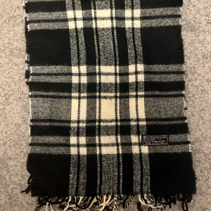 Rutig svartvit halsduk från Burberrys - Snygg halsduk från Burberry i klassiskt rutigt mönster. Tillverkad i 100% lammull, mjuk och varm. 