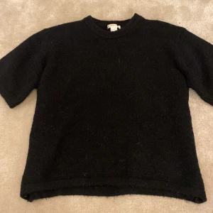 Svart stickad tröja Gina Tricot - En svart stickad tröja från Gina Tricot. Storlek 170 men skulle säga att den är lite mindre i storleken.rund halsringning och korta ärmar. Enkel och stilren modell som passar perfekt till lager-på-lager. Mjuk och skön känsla tack vare det stickade materialet.