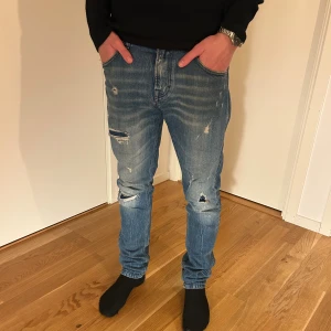 Blå slitna Replay jeans  - Snygga blå jeans från Replay med slitningar och trasiga detaljer på benen. Modellen är skinny och har klassisk femficksdesign. Jeansen har en ljus tvätt med markerade whiskers och är tillverkade i jeansmaterial. Perfekt för dig som gillar en tuff och avslappnad stil. Passar bra för någon som är 178cm