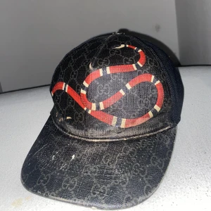 Svart Gucci keps med röd orm - Tjena!!  byter min Gucci keps för att jag vill ha en annan Gucci keps då jag tröttnat på denna , kepsen är sliten och de finns hår spray i den för förra ägaren ägde den han sa att han hade haft hårspray på sig sen haft kepsen då det går bort om man tvättar den men de inte så viktigt för de inuti och man ser inte men om ni vill se mer bilder skriv privat till mig eller om ni är intresserad utav den finns i Skåne !! 