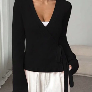 Svart omlott kofta med knytband - Svart omlott kofta med långa ärmar och snygg v-ringning. Koftan har ett knytband i midjan som ger en schysst passform och lite extra stil. Materialet är stickat och känns mjukt mot huden. Perfekt att slänga på sig när det är lite kyligare ute. Jätte fin och knappt använd, bra material för kyliga dagar! Fint för vintern! Pris kan diskuteras 