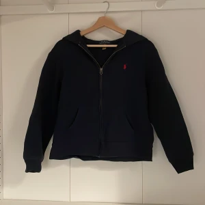  Polo Ralph Lauren tröja - Säljer en mörkblå hoodie från Polo Ralph Lauren med dragkedja och huva. Perfekt nu inför hösten säljer för att den e för liten.