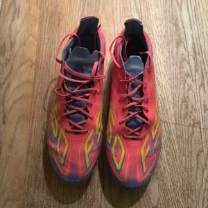Adidas F50 rosa fotbollsskor FG - Säljer ett par Adidas F50 fotbollsskor i en riktigt snygg rosa och gul färg med blå detaljer och använda få tal gånger.Perfekta för dig som vill sticka ut på fotbollsplanen!