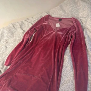 Sammetklänning från Gina Tricot - fuschia klänning i mjuk sammet från Gina Tricot. Modellen heter Florentina dress och har långa ärmar, figurnära passform och v-ringad hals. Prislappen är kvar!