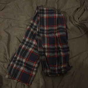 Rutig mjukisbyxa med snörning - Mysiga mjukisbyxor i mörkblått, rött och vitt rutmönster. Byxorna har resår och snörning i midjan för extra komfort. Perfekta för chill dagar hemma eller när du vill vara extra bekväm.