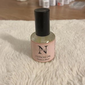 Nageloljan Vanilla Bean Nagel Experten - Nagelolja med doft av vanilj från Nagel Experten. Kommer i en rund glasflaska med svart skruvkork och ljusrosa etikett. Perfekt för att återfukta och vårda nagelbanden. Innehållet är genomskinligt och lättflytande. 20-30% använd!