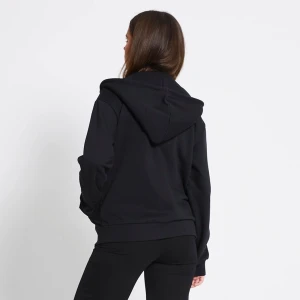 Svart hoodie med dragkedja och huva - Svart hoodie med dragkedja framtill och stor huva. Tröjan har snörning vid huvan, ribbade muddar och en loose passform. Tillverkad i mjuk bomullsmix som är skön att ha på sig. Perfekt för chill dagar och enkel att matcha med jeans eller leggings.