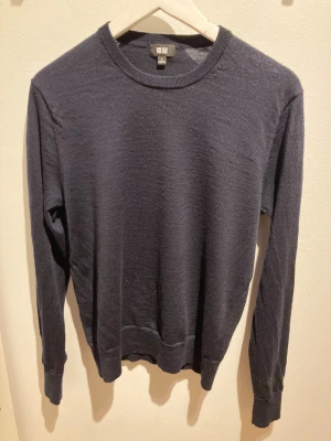 Mörkblå stickad tröja från Uniqlo - En enkel och stilren mörkblå stickad tröja från Uniqlo i storlek S. Tröjan har rund hals, ribbade muddar och lång ärm. Perfekt för lager-på-lager och chill stil. Materialet är mjukt och lätt, vilket gör den skön att bära under höst och vinter. Tröjan är endast provad då det blev ett hål i tröjan men annars är den fin. Bara höra av er om ni undrar över något 