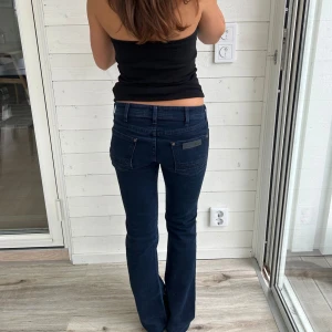 Mörkblå jeans  - Omsydda mer lågmidjade än på bilden men mörkblå wrangler jeans med fina mönster på. Storlek: S/XS midjemått: 37x2 cm innerbenslängd: 76 cm. Modell på bilden: ca 160 cm