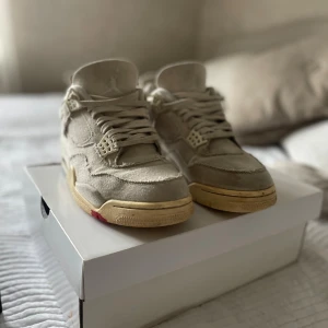 Nike Air Jordan 4 Retro Sail Canvas - Nike Air Jordan 4 Retro i färgen sail/cement grey med canvas-överdel och slitna detaljer. Snygg vintage-look med beige och grå toner, klassisk siluett och ikoniska meshpaneler. Platt sula och snörning. Perfekt för dig som vill sticka ut med en unik sneaker.