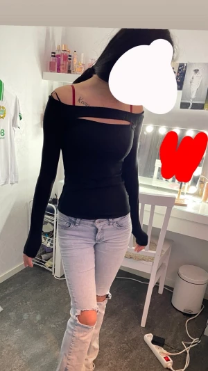 Svart offshoulder långärmad topp - Säljer en svart, tight offshoulder topp med lång ärm och cool cutout-detalj över bröstet. Toppen har en slim passform och är perfekt för dig som gillar en stilren och edgy look. Materialet känns mjukt och stretchigt, vilket gör den skön att bära.