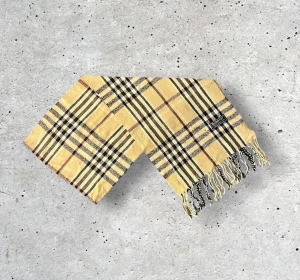 Beige Burberry Scarf - ✨ Klassisk Burberry-halsduk i 100% ull – ikonisk beige ✨ Säljer en tidlös Burberry-halsduk i den klassiska beige färgen med det välkända rutmönstret. Tillverkad i 100% mjuk och värmande ull som både känns lyxig och håller hög kvalitet. En perfekt accessoar som lyfter vilken outfit som helst — lika fin till vardagsjackan som till en elegant kappa.  🧵 Skick: Mycket fint skick, väl omhändertagen 🌟 Känsla: Mjuk, varm och följsam 📦 Frakt: Skickas tryggt inom 24h 📏 Mått: Längd-175cm, Bredd-34cm