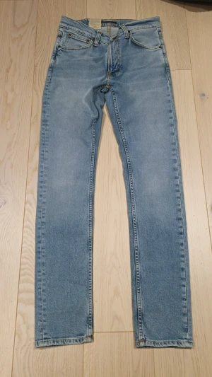 Nudie Jeans Lean Dean Warm Days Blue - Sprillans nya Ljusblå Lean Dean jeans från Nudie Jeans med klassisk femficksdesign, snygga kontrastsömmar och broderad detalj på bakfickorna. 
