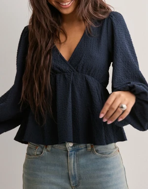 Mörkblå blus med v-ringning - Heeej! Jag säljer en mörkblå blus med v-ringad omlottfront och voluminösa långärmar. Blusen är använd 1-2 gånger och är i nyskick. Säljer pågrund av att den ej kommer till användning 💖