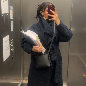 Mörkblå gina kappa - Säljer en lång och oversized mörkblå teddyjacka med bälte i midjan. Jackan har en bred krage och är gjord i mjukt fleece-material som ger en cool och mysig vibe. Perfekt för dig som gillar att sticka ut med en chunky look och vill hålla dig varm under hösten och vintern.