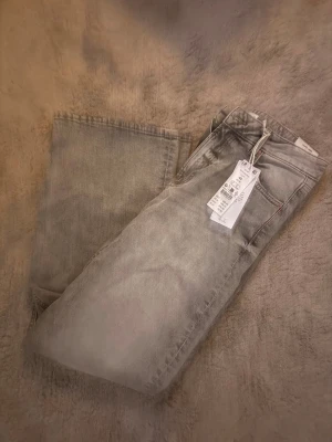 Grå raka jeans med tvättad look - Snygga grå jeans med tvättad effekt och raka ben. Klassisk femficksmodell med normal passform och dragkedja. Perfekta för en avslappnad stil och lätta att matcha med det mesta.
