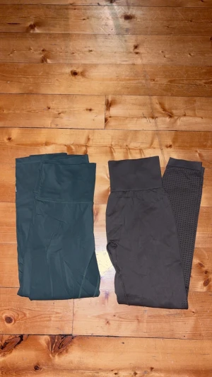 Två par leggings i grönt - Säljer två par snygga leggings, ett par i mörkgrönt och ett par i en ljusare grön med perforerade detaljer på benen. Båda har bred midja för extra komfort och är perfekta för träning eller chill. Materialet är stretchigt syntet som sitter skönt och följer kroppen. säljer ihop. 