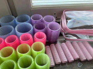 Färgglada hårspolar i plast med väska - Säljer ett set med hårspolar i olika storlekar och färger: blå, lila, rosa, grön och ljusrosa. Spolarna är gjorda av plast med kardborre och kommer med en genomskinlig necessär med rosa kant. Perfekt för att fixa volym och lockar hemma.