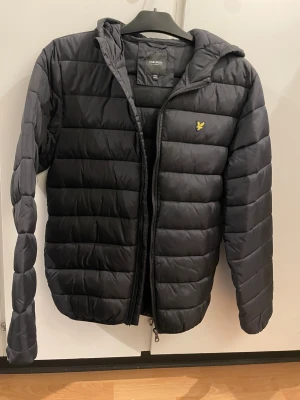 Oanvänd Lyle & Scott jacka - äkta varumärke  - Oanvänd svart Lyle & Scott jacka i strl 14/15 år. Köpt från kids Brands Store. Passar både kille och tjej. 