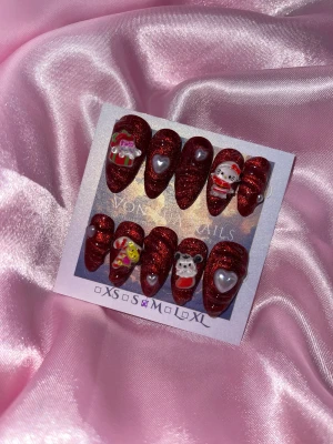XmasSan (M);Medium Almond - Säljer ett set med handgjorda press-on naglar i glittrigt röd färg med spetsig form. Naglarna har 3D dekorationer som Hello Kitty i tomtedräkt, hjärtan, nalle och julklapp, samt vita detaljer. Perfekt för dig som vill ha extra cute och festliga naglar.M: 16 mm, 12 mm, 12,5 mm, 11,5 mm, 10 mm