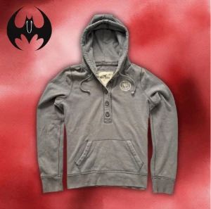 Grå hoodie Hollister med tryck - Grå hoodie från Hollister med tryck och vit markerade text i höger ’Hollister’ | Size S/M | längd: 68cm armlängd: 70cm axelbredd: 42cm | passar för 165-176 cm 