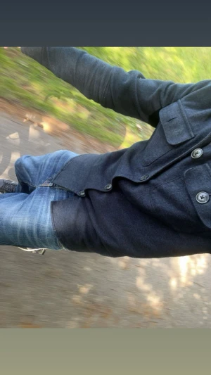 Mörkblå overshirt från JACK AND JONES - Snygg mörkblå overshirt från Indigofera med klassisk krage och stora bröstfickor med knappar. Materialet är tjockt och mjukt, troligen ull, perfekt för lager-på-lager. Stängs med rejäla knappar framtill och har en cool orange insida vid nacken.