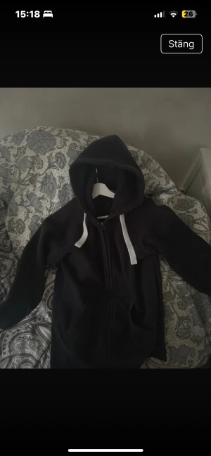 Mörkblå hoodie från Russedress, M - Mörkblå hoodie från Russedress i storlek M med vit snörning i huvan och hel dragkedja framtill. Tröjan har långa ärmar, två fickor och en extra ficka med dragkedja på insidan. Mjuk insida i fleece som gör den extra skön. Perfekt för chill eller häng.