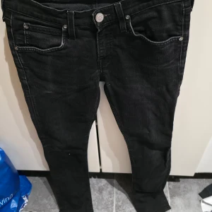 Svarta skinny jeans från Lee Luke W27 L32 - Svarta jeans från Lee Luke med skinny passform och klassisk femficksdesign. Tillverkade i stretchigt material med 98,5% bomull och 1,5% elastan för extra komfort. Snygga detaljer med Lee-logga på knappen och smal siluett.