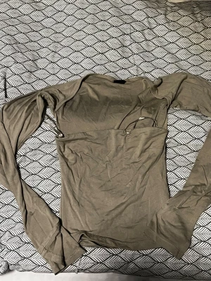 Olive grön långärmad topp Gina Tricot XS - Säljer en beige långärmad topp från Gina Tricot i storlek XS. Toppen har en slim passform och är tillverkad i mjuk bomull med stretch. Den har en enkel och stilren design med rund hals och smala ärmar, perfekt att styla med jeans eller kjol.