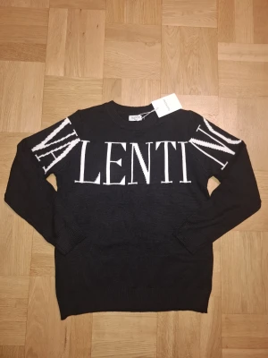 Valentino stickad tröja  - Cool svart stickad tröja från Valentino med stor vit logotyp över bröstet och axlarna. Rund hals och långa ärmar med ribbade muddar. Perfekt för dig som gillar statement-plagg och italiensk design. Pris kan diskuteras!!!